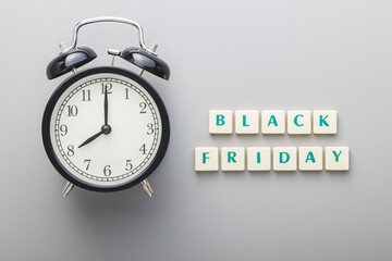 Black friday text and alarm clock on gray background. Top view.