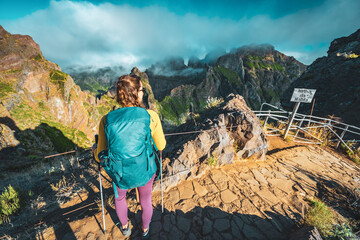 Woman enjoying the mountain scenery of Pico Ruivo from a viewing platform with very steep cliff in...