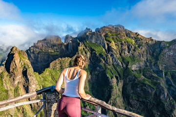 Woman enjoying the mountain scenery of Pico Ruivo from a viewing platform with very steep cliff in...