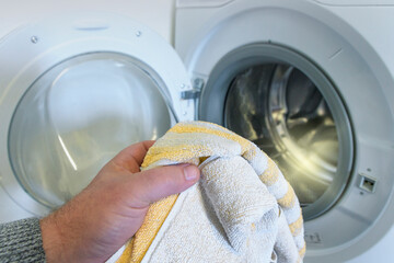 washing light-colored clothes in the washing machine. man holding a towel