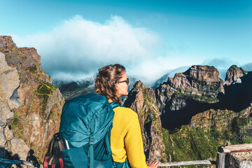 Woman enjoying the mountain scenery of Pico Ruivo from a viewing platform with very steep cliff in...