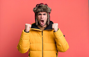 adult man shouting aggressively with an angry expression wearing anorak. winter and cold concept