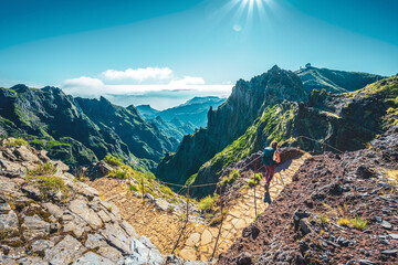 Woman with backpack hiking along very scenic hike trail to Pico Ruivo in the morning. Pico do...