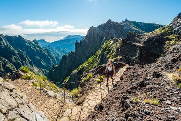 Woman with backpack hiking along very scenic hike trail to Pico Ruivo in the morning. Pico do...