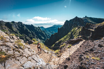 Woman with backpack hiking along very scenic hike trail to Pico Ruivo in the morning. Pico do...