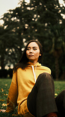 The girl in the park sits on the grass and looks away