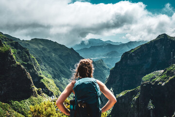 Woman enjoying mountain scenery from very scenic view point along hike trail to Pico Ruivo at noon....