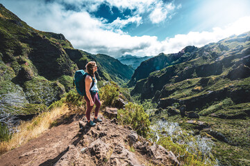 Woman enjoying mountain scenery from very scenic view point along hike trail to Pico Ruivo at noon....