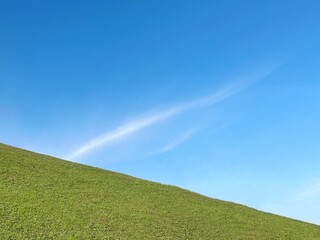 Green grass hill and blue sky at sunny day.