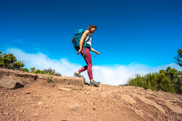 Hiker with backpack walking down a step along the hiking trail on Pico Ruivo. Verade do Pico Ruivo,...