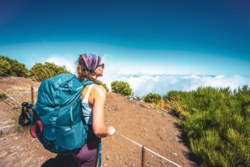 Hiker with backpack enjoying the view of the summit of Pico Ruivo at noon. Pico do Arieiro, Madeira...