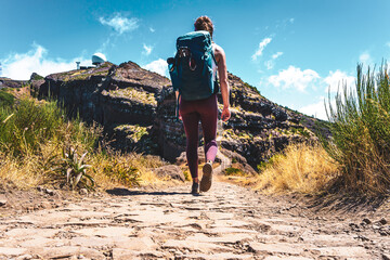 Sportive woman with backpack walking along scenic hike trail to Pico do Ariero in the afternoon....
