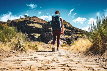 Sportive woman with backpack walking along scenic hike trail to Pico do Ariero in the afternoon....