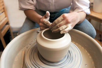 Close-up of potter's hands. An artisan works on a potter's wheel and makes a vase. Creating ceramics
