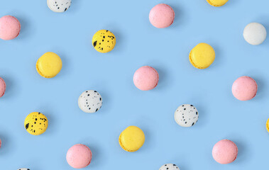 Many different macaroons pattern on blue background. Pink, white and yellow French cookies....