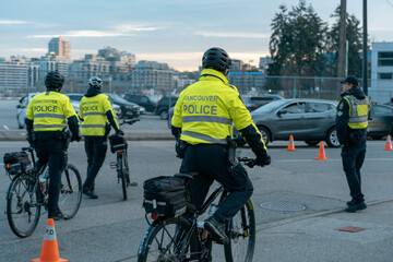 Vancouver Canada - November 21, 2021: A Vancouver police officer on a bike patrols near Downtown Vancouver with the city skyline in the background