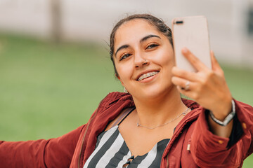 young woman with braces using mobile phone smiling