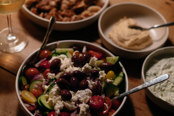 Plates of homemade rustic greek food on a table with greek salad calamari hummus wine and beer