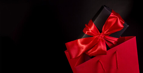Happy Valentine's Day or Black Friday Shopping Concept with Black Gift Box and Red Satin Bow...