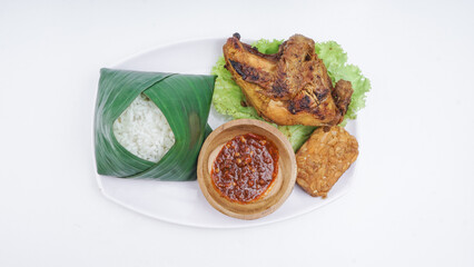 Ayamn Bakar or Grilled Chicken with rice, sambal, fried tempeh, and lettuce. Indonesian popular food