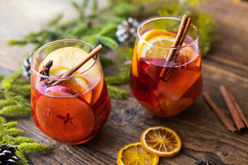 Glasses of hot mulled wine with fresh fruit apples and oranges. Traditional winter drink
