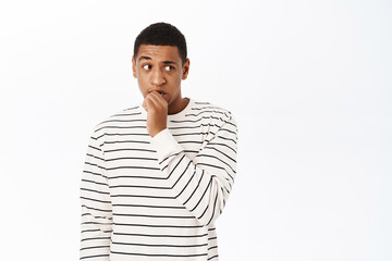 Anxious middle aged african american man, biting fingers, looking scared or nervous, standing over white background