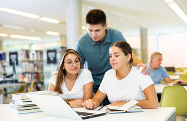 Friendly happy group of students preparing together for exam in modern university library