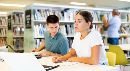 View on young european students studying together with a laptop in library