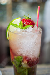 Bartender making refreshing coctail on a bar background. Dark moody style. Ice in tha glass