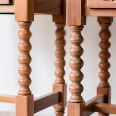 Close-up detail of a pair of legs of an old and antique wooden furniture with selective focus and selective lighting on them.
