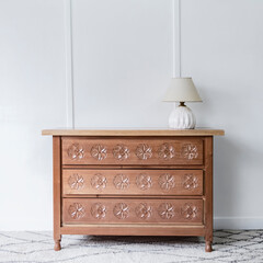Front view of a quaint and beautiful chest of drawers standing alone in a room lit by natural light.
