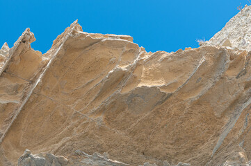 Rock is orange in color against blue sky without clouds. Texture background of rock and sky.