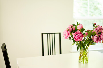 a white table with a piony's vase and   chairs