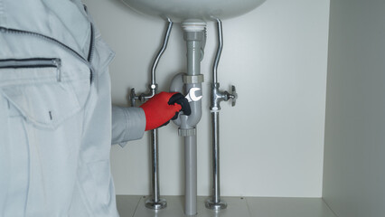 洗面台下の配管修理イメージ｜スパナを持った作業員