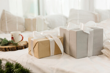 Christmas gifts on the bed on a white sheet. Spruce branch. Cozy morning.