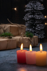 christmas gifts on the tree, behind candles, concept waiting for christmas