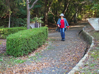 森林公園を歩く高齢日本人女性