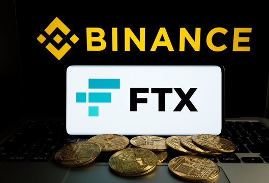 Binance and FTX Cryptocurrency Exchange merger concept. FTX logo seen on smartphone, fallen stack of bitcoin tokens, Binance logo on a laptop. Stafford, United Kindom, November 9, 2022.