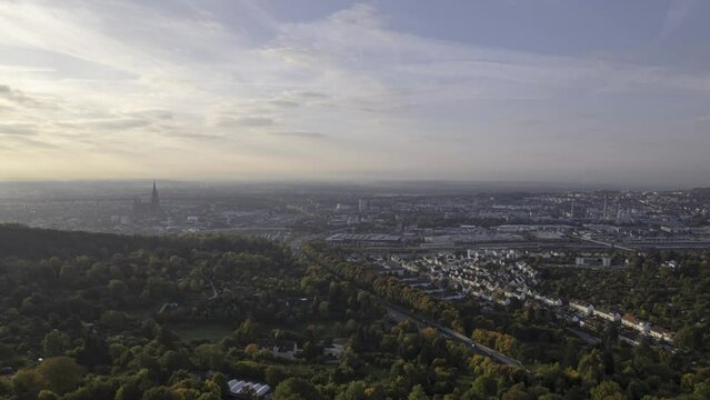 Revealing Ulm city behind forest at morning in autumn aerial time lapse
