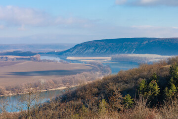 Obraz premium Beautiful view of the hilly valley with the river soothing winter nature. Background with copy space
