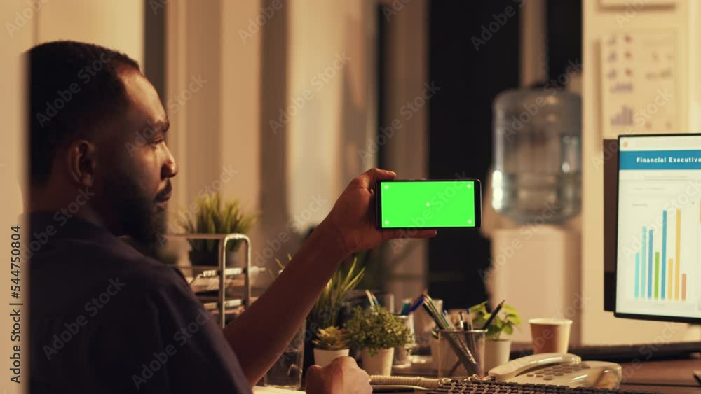 Poster african american man using smartphone with greenscreen, looking at mobile phone with blank copyspace