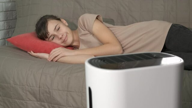 Girl sleep at home with humidifier. A smiling young girl lay and enjoy her new aur purifier during self isolation at home.