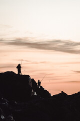 silhouette of a person on a rock fishing