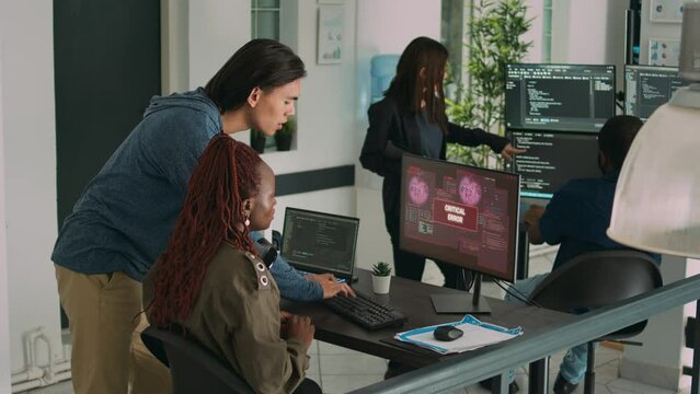 Diverse team of app developers having computer hacked and writing code, encountering unexpected system error in software development office. Coders having server failure while creating algorithm.