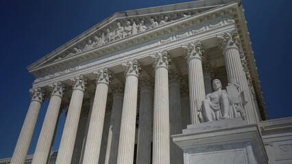 Obraz premium Facade of US Supreme Court building with Authority of Justice sculpture in front in Washington DC on a sunny summer evening.