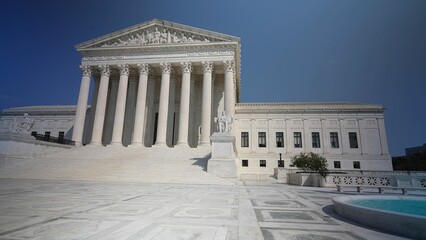 Wide angle view of facade of US Supreme Court building with Authority of Justice sculpture in front on a sunny summer day.