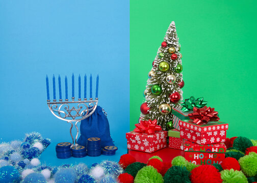 Hanukkah menorah with blue candles next to Christmas tree with presents. Many multi faith families celebrate both Xmas and Hanukkah. Chrismukkah.