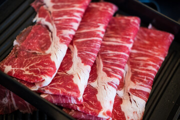 Fresh beef raw sliced with marbled texture served for sukiyaki, shabu or yakiniku