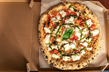 Mozzarella bufala pizza in a box, take away, ordered vegetarian italian food, basil pesto