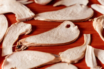 Sliced mushrooms drying on a red wooden surface, detail